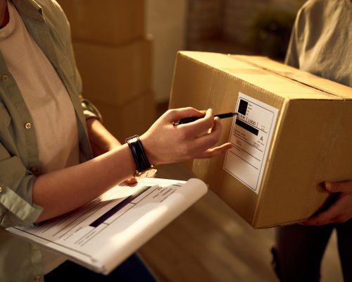 two-delivery-women-cooperating-while-checking-data-packages-office
